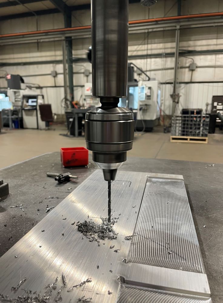 Drill press operator drilling holes in aluminum plate